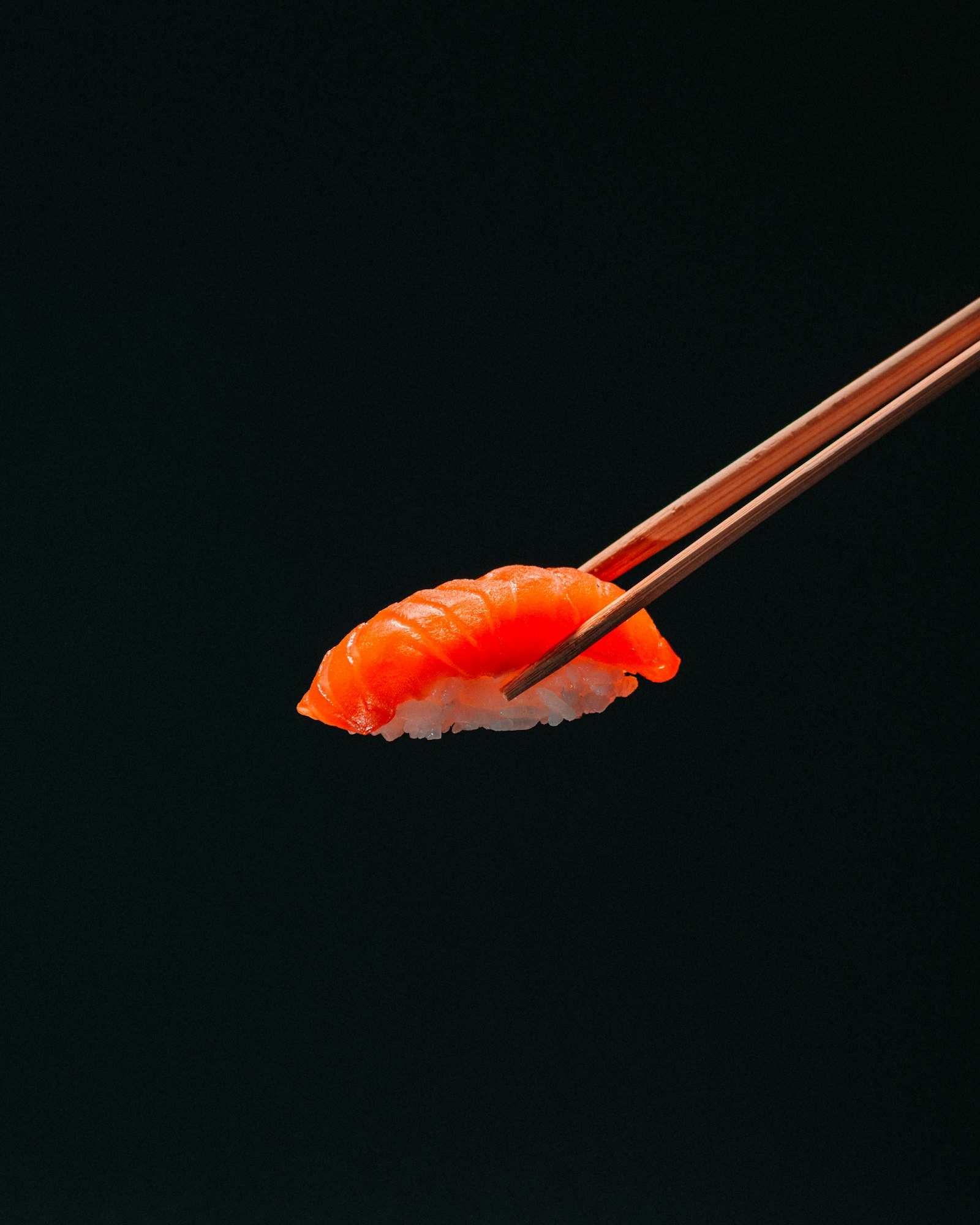 Nigiri salmon diapit sumpit kayu