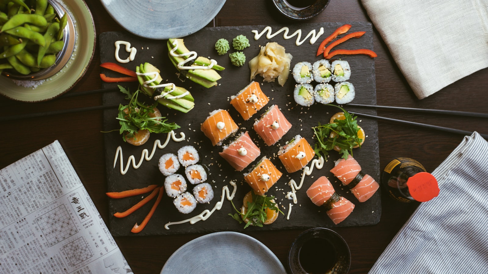 Aneka sushi dan sashimi tersaji di atas papan batu